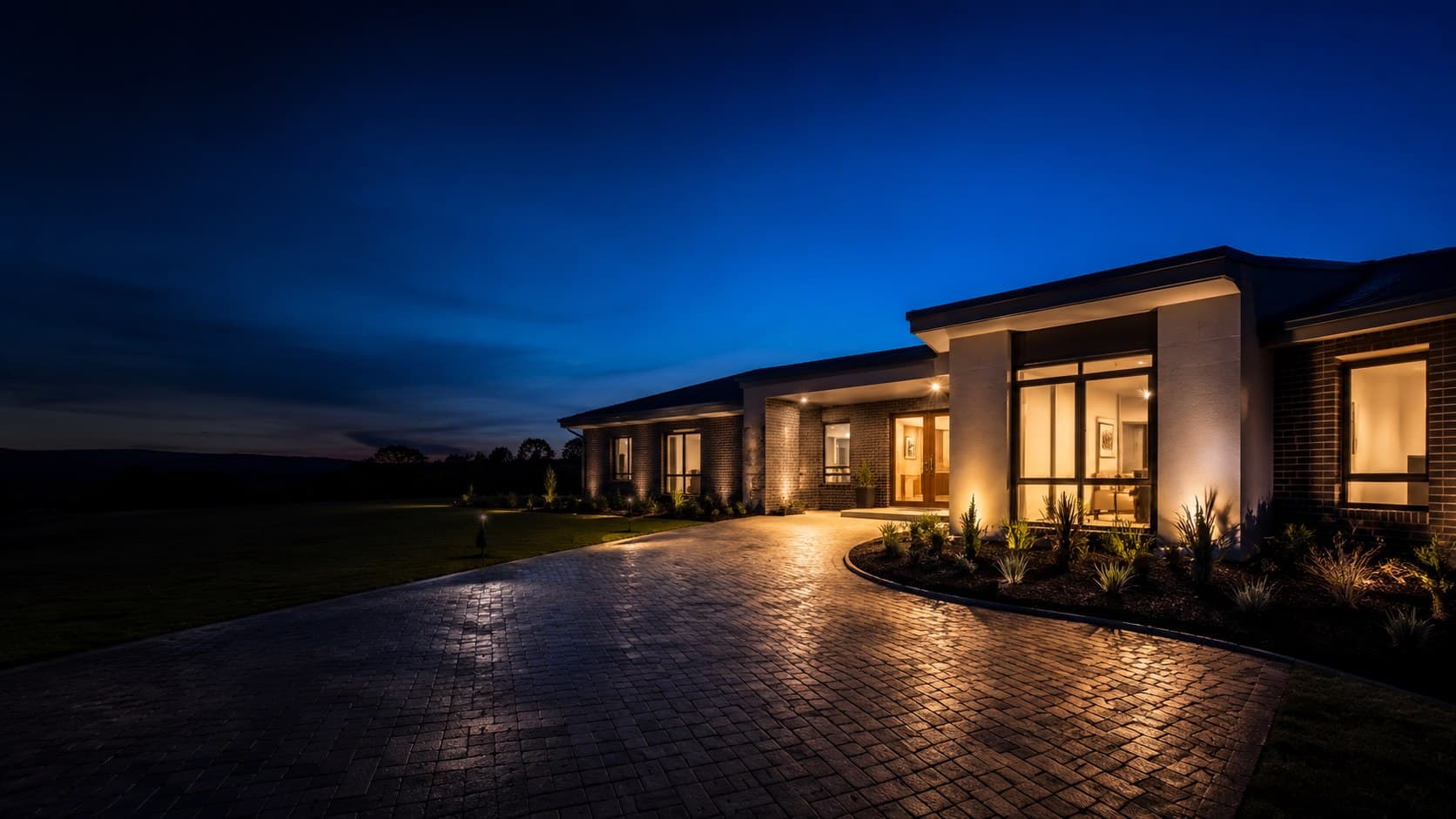 Newly built modern home at blue hour with warm glowing windows